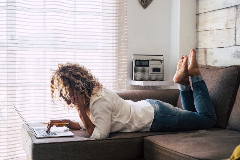 Adult female at home working and doing progress about her future on the sofa in her workplace - lying down woman alone work