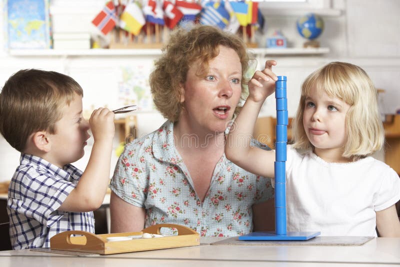 Adult Helping Two Young Children at Montessori/Pre School Child concentrating really hard