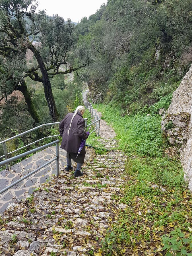 Adult lady walking  downhill in long narrow mountain street in Vrosina village  , Ioannina perfecture Greece