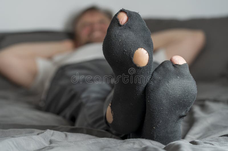 Side view of socks with a hole on the man's legs - Stock Photo