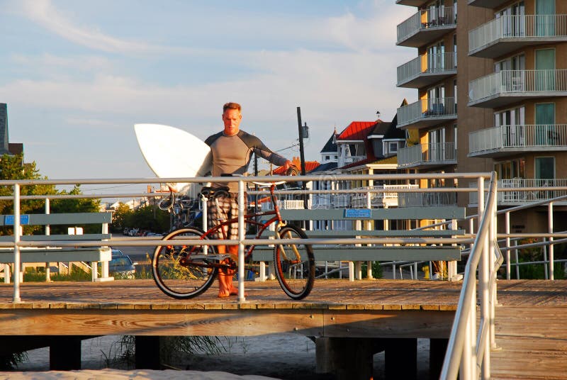 An adult man parks his bike before going surfing stock photography An adult man parks his bike before going surfing stock photography