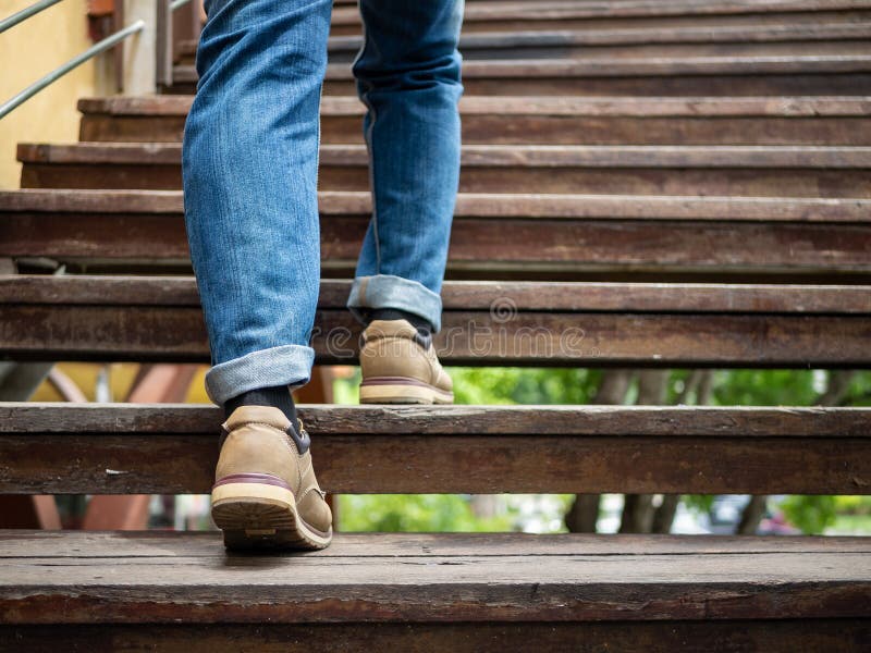 Adult man walking up the wooden stairs. Moving forward Concept.