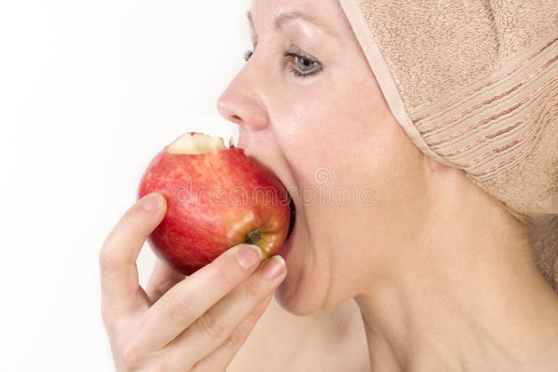 Adult woman is biting an apple.