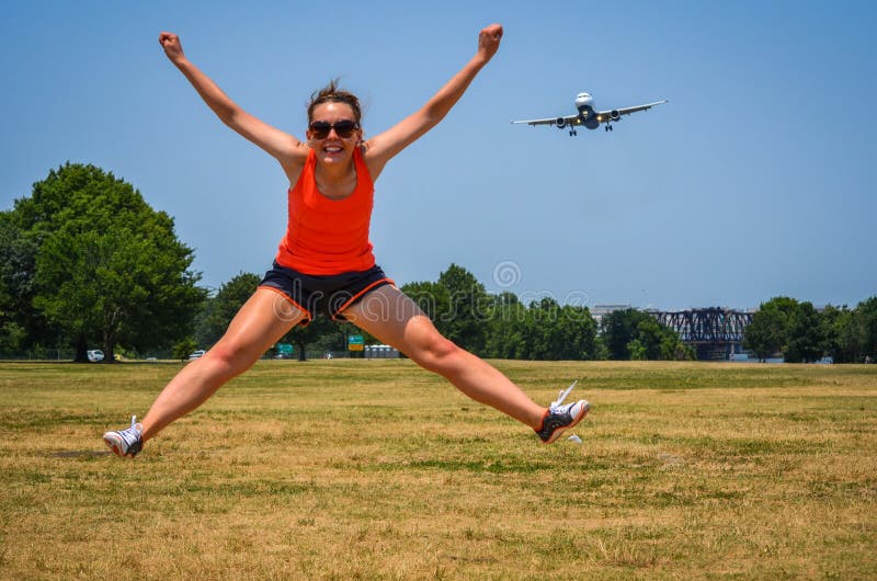 Adult woman at Gravelly Point Park in Washington DC jumps as an airplane flies in for a landing at the DCA Reagan International