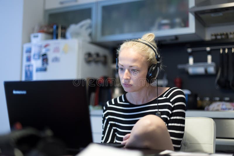 Adult woman in her casual home clothing working and studying remotely from her small flat late at night. stock image Adult woman in her casual home clothing working and studying remotely from her small flat late at night. stock image