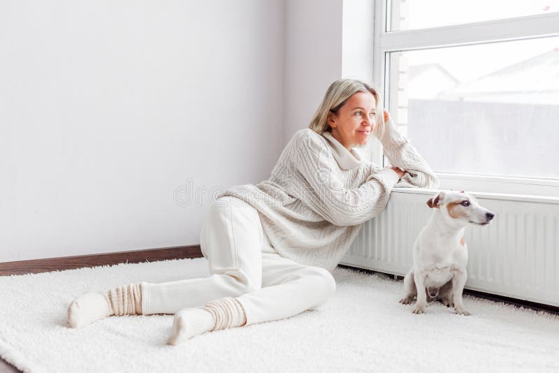 Adult woman near radiator looking on window in the living room