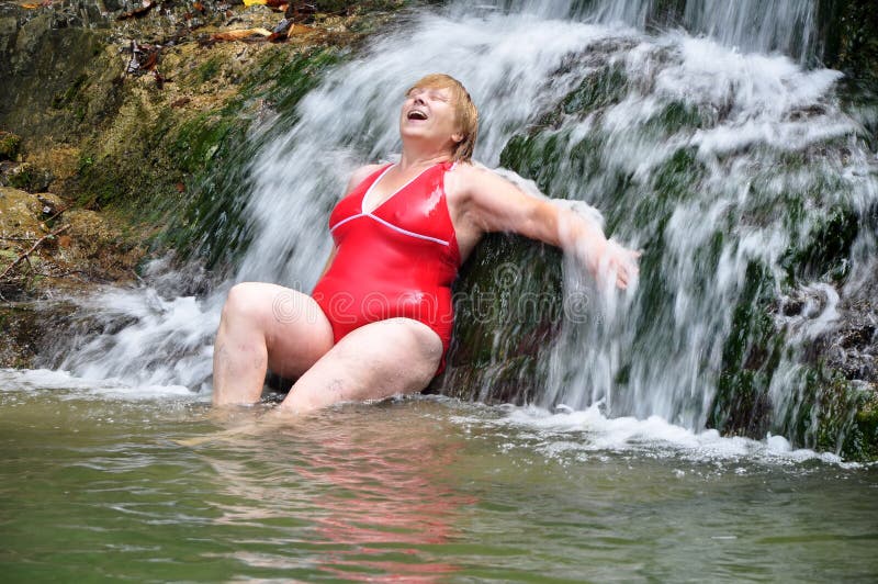 Adult woman in red swimsuit enjoying a waterfall