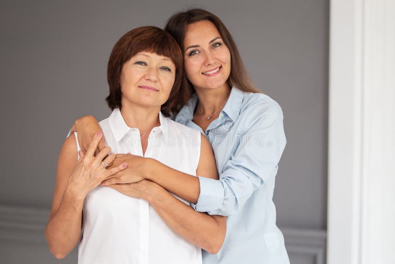 Adult woman hugs her elderly mother and they both smiling. 