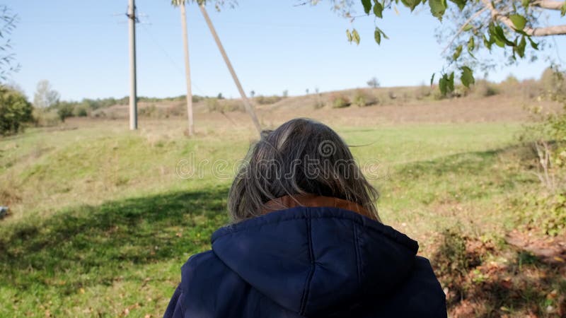 Adulto cammina verso il fiume lungo una strada di campagna Visualizza dal retro Movimento lento Chiudi stock footage