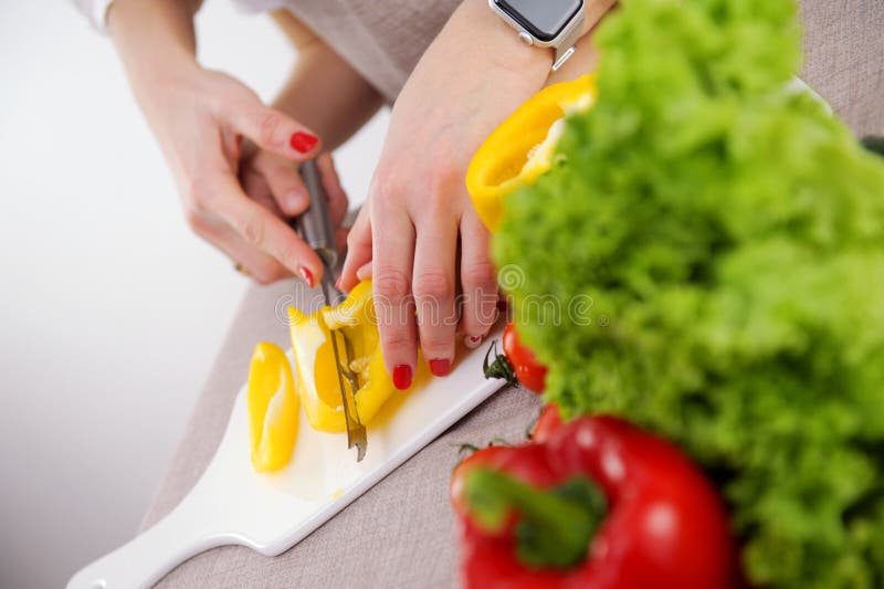 Adulto enseña a los niños a cortar verduras la madre ayuda al hijo a cortar pimiento amarillo closeup manos cuchillo y porcelana foto de archivo