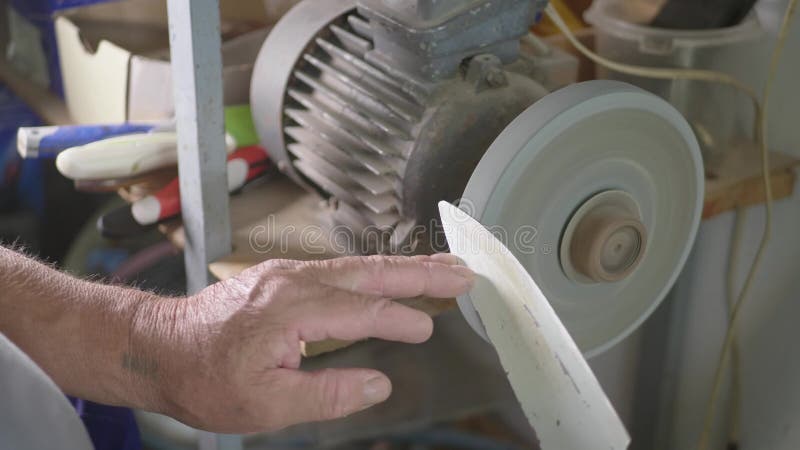 Adulto especialista em afiação de faca de aço na lata da roda Moagem de homem com pedras abrasivas de corte e afiação de facas