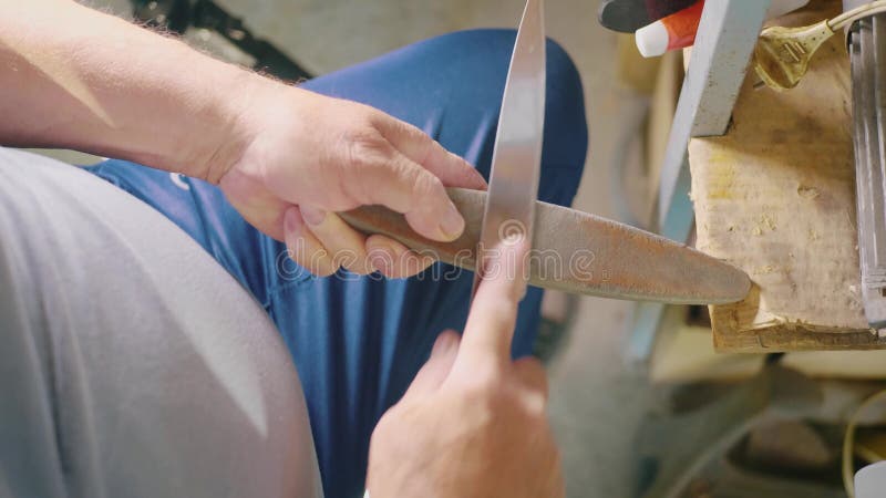 Adulto especialista em afiação de faca de aço na lata da roda Moagem de homem com pedras abrasivas de corte e afiação de facas