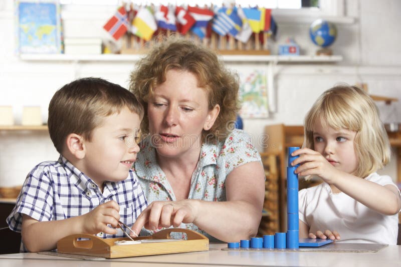 Adulto que ajuda duas crianças novas em Montessori/Pr