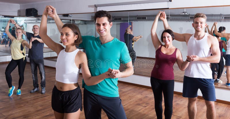 Smiling adults dancing bachata together in dance class. Smiling adults dancing bachata together in dance class