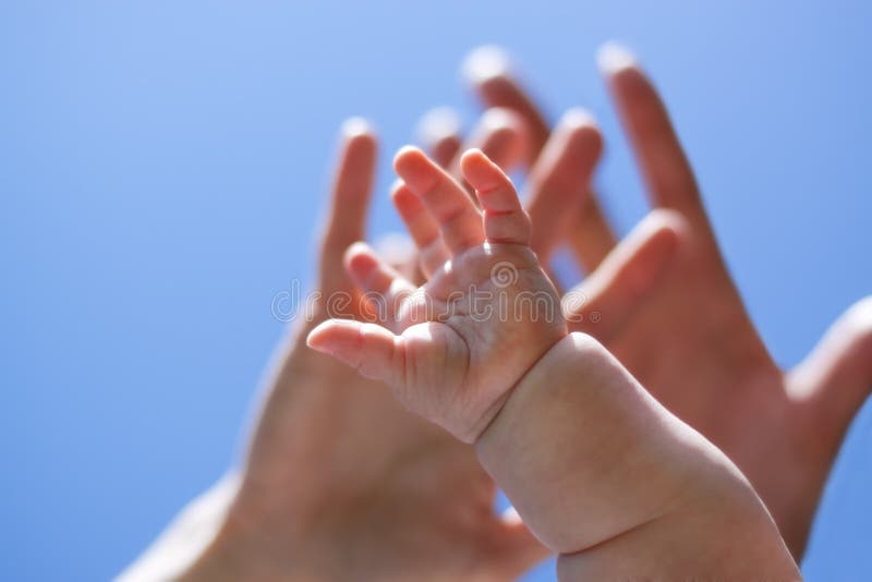Adults and babys hand in front of blue sky