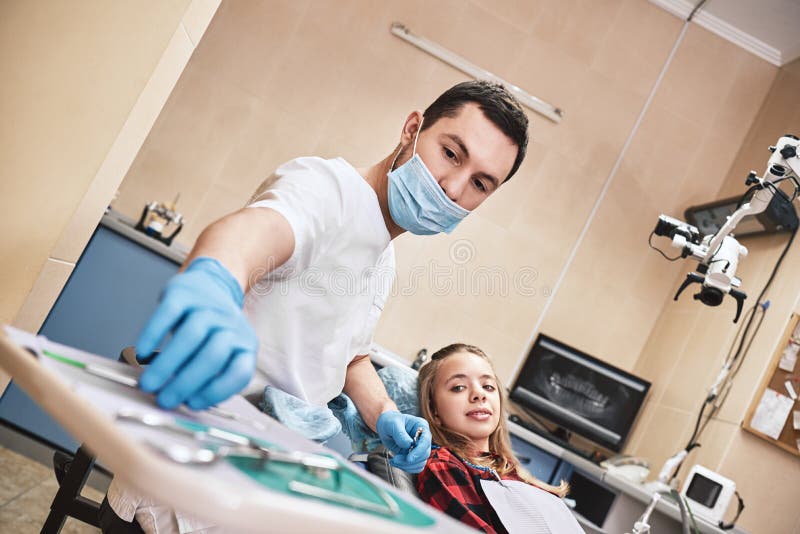 Advanced Medicine, Trusted Care. Teen at the dental office. Dentist treats teeth, girl lying in the dental chair royalty free stock photography Advanced Medicine, Trusted Care. Teen at the dental office. Dentist treats teeth, girl lying in the dental chair royalty free stock photography