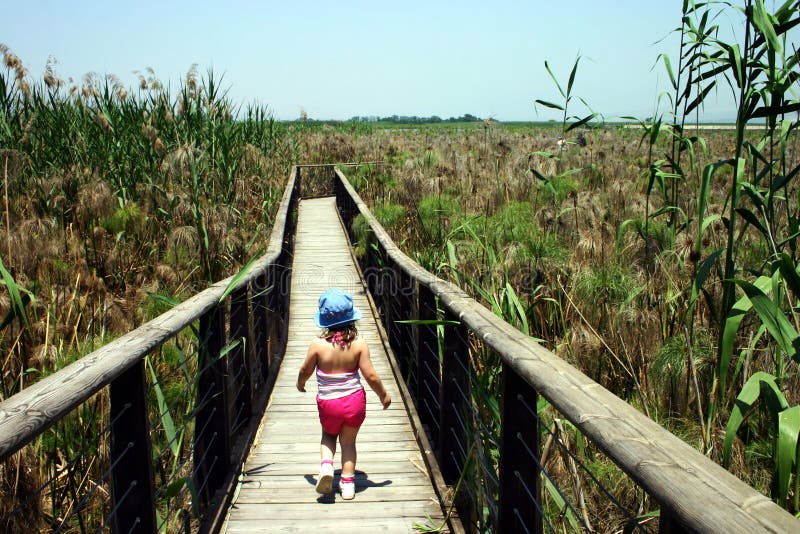 Bambina camminando su un ponte di legno.