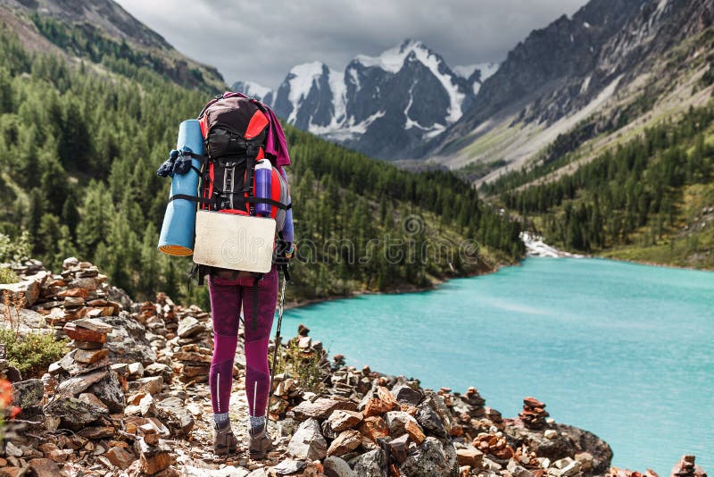 Backpacking woman enjoying view of majestic blue mountain lake in Altai