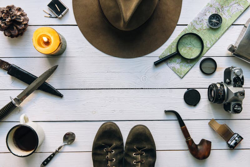 Adventure planning flat lay. Travel vintage gear on white wooden table. Including film camera, hat, knife, magnifier, compass.