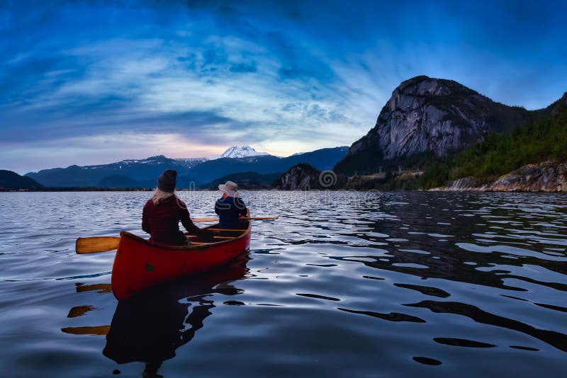 Adventurous people on a canoe with Mountains Behind