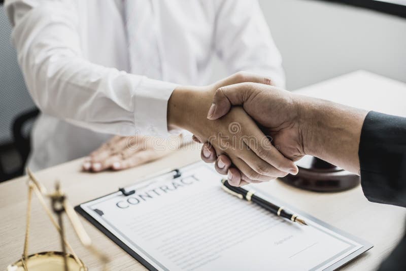 Lawyer and client shake hands, after winning a lawsuit where a lawyer hired by a client in a fraud case and proceeding in a fair and correct manner, the client wins the case. Fraud litigation concept. Lawyer and client shake hands, after winning a lawsuit where a lawyer hired by a client in a fraud case and proceeding in a fair and correct manner, the client wins the case. Fraud litigation concept