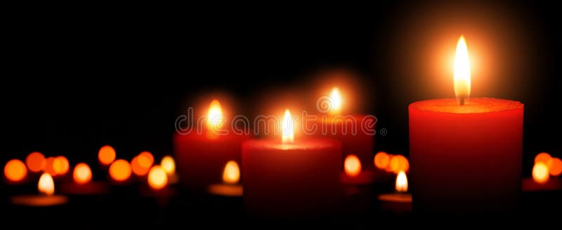 Low-key studio shot of elegant advent candles with four flames in the foreground, black background with defocused flames. Low-key studio shot of elegant advent candles with four flames in the foreground, black background with defocused flames