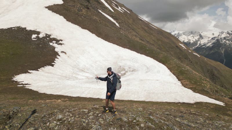 Aerial of backpacker hikes Svaneti mountains. Traveler explores snowy peaks, spreads arms, stunning landscape. Adventure stock video footage