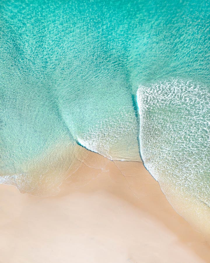 Aerial of a beach with beautiful waves, white sand and ocean textures