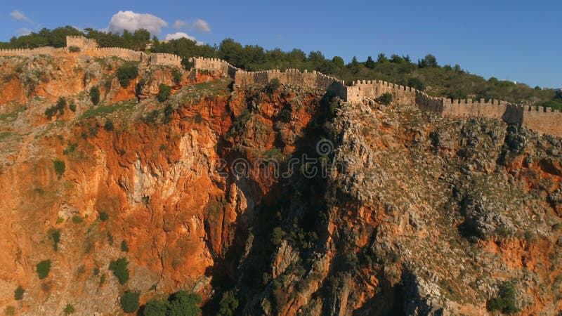 Aerial copter flight over Alanya Fortress walls on rocky Taurus Mountains covered with thick green forests and