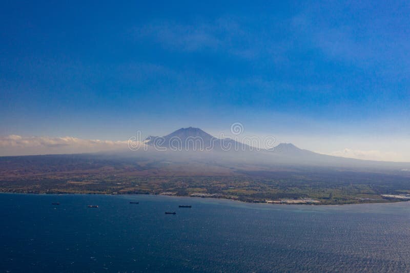 Aerial view of beautiful seascape with boats over island with volcano background in Indonesia. Aerial drone view of beautiful seascape with boats over island stock photo Aerial view of beautiful seascape with boats over island with volcano background in Indonesia. Aerial drone view of beautiful seascape with boats over island stock photo