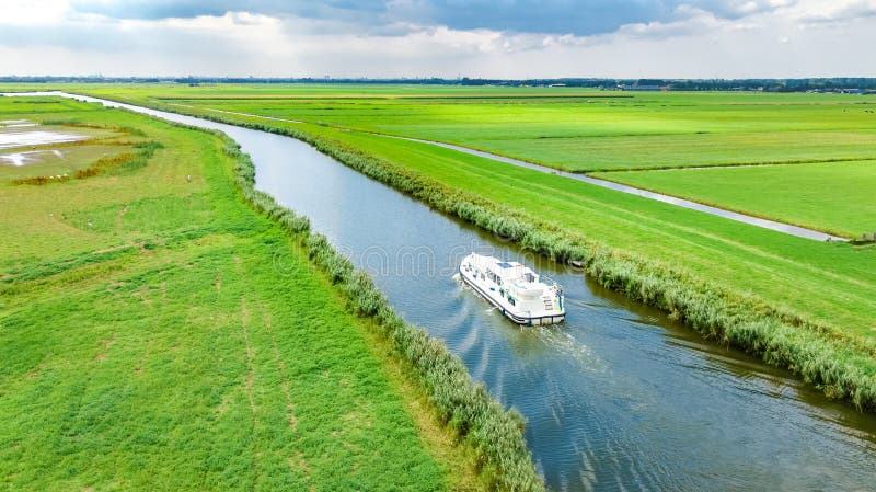 Aerial drone view of houseboat in canal and country landscape of Holland from above, family travel by barge boat and vacation