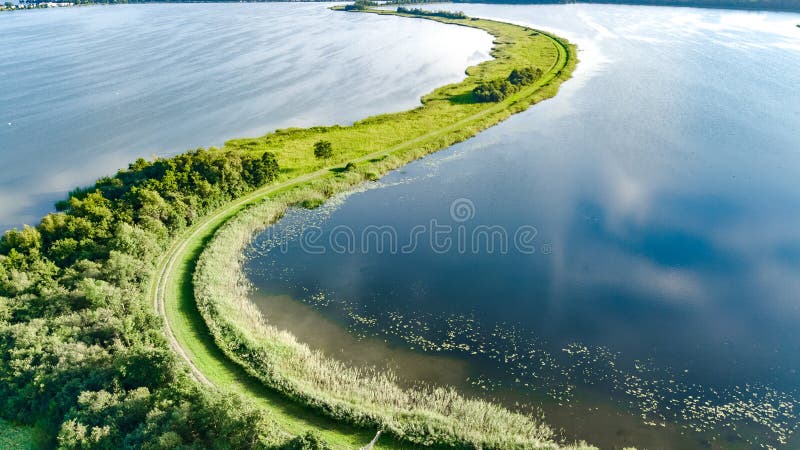 Aerial drone view of path on dam in polder water from above, landscape and nature of North Holland in Netherlands