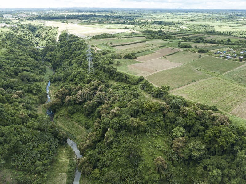 Aerial of an electric pylons running along a river gorge and undeveloped farmland in Dasmarinas Cavite