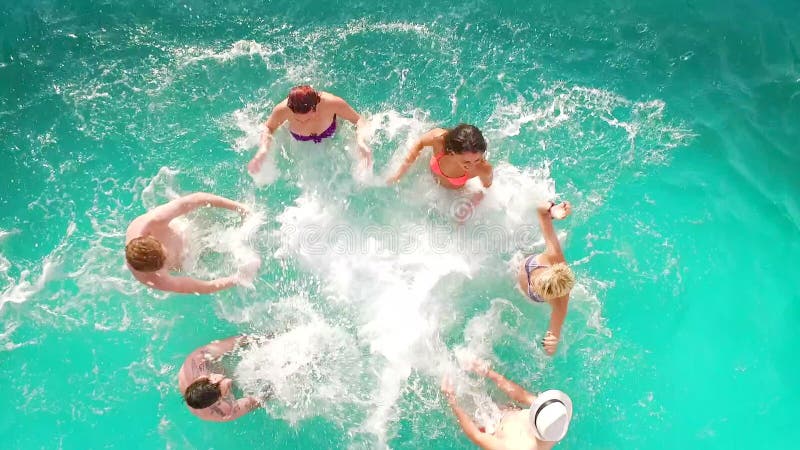 Aerial flight : Happy group of friends enjoying pool party splashing in water