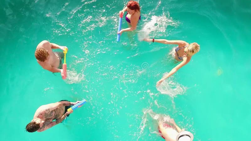 Aerial flight : Happy group of friends enjoying pool party splashing in water