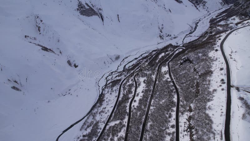 Aerial footage of a winding road passing through a snowy mountain in Armenia during daytime stock video footage