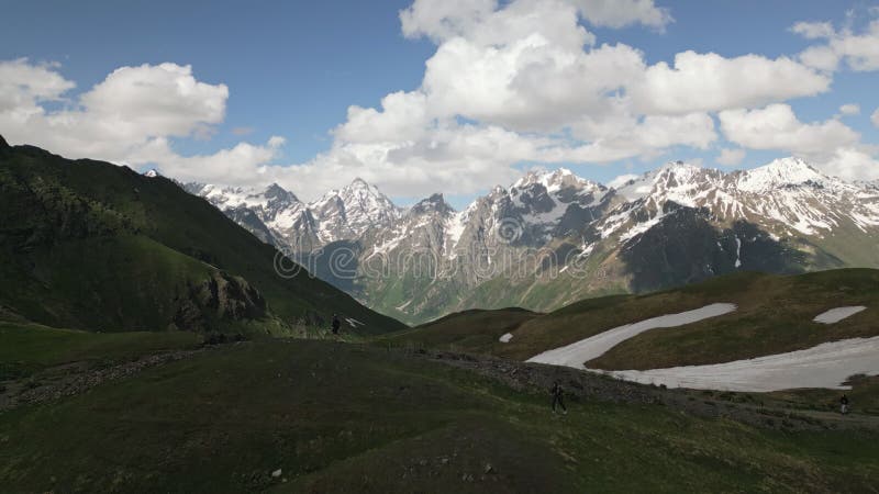 Aerial of hikers trek Koruldi Lakes near Svaneti peaks. Scenic mountain landscape, serene lakes, snowy summits, clear stock video