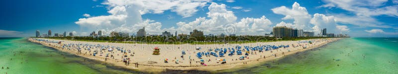 Aerial panoramic photo Miami Beach summer. Tourists sunbathing on Florida coastline iconic hotels visible on Ocean Drive USA