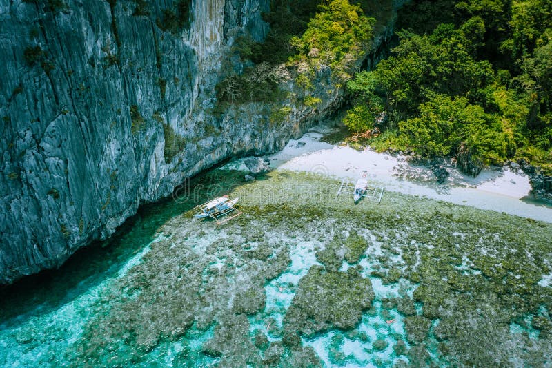 Aerial Photo of banca boats moored at white sand paradise beach and people snorkeling over colorful coral reefs in El royalty free stock image Aerial Photo of banca boats moored at white sand paradise beach and people snorkeling over colorful coral reefs in El royalty free stock image