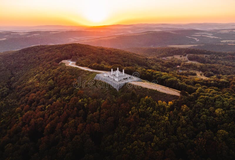 Aerial photo by drone of The Barrow cairn of Milan Rastislav Stefanik upon Hill with beautiful green trees around - on sunset.