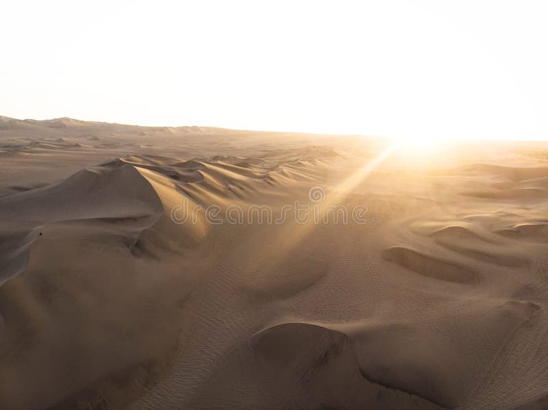 Aerial postcard panorama sunset view of isolated lonely single man person dry sand dunes desert of Huacachina Ica Peru