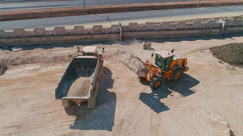Aerial shot of a large loader loading a truck in a construction site stock video