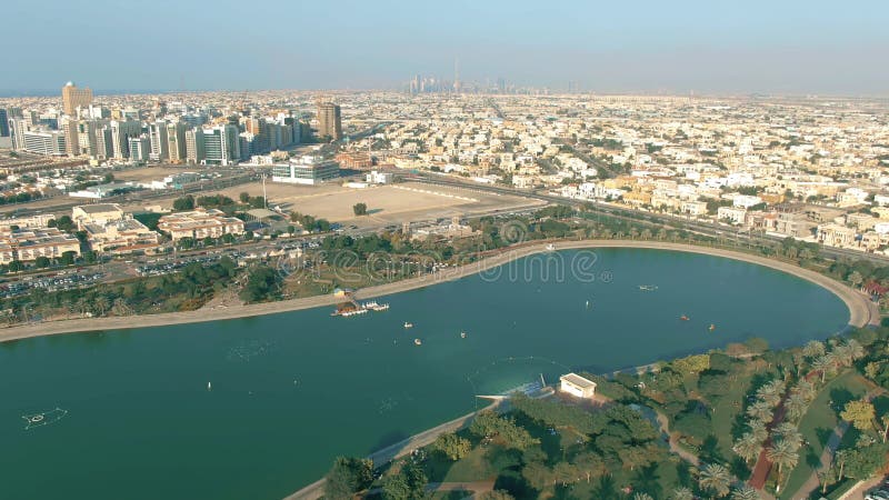 Aerial view of seafront part of the city and Dubai Downtown behind Al Barsha Pond Park, UAE