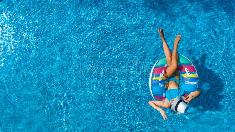 Aerial top view of beautiful girl in swimming pool from above, relax swim on inflatable ring donut in water on family