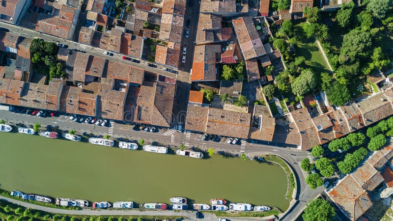 Aerial top view of Castelnaudary residential area houses roofs, streets and canal with boats from above, old medieval town background, France