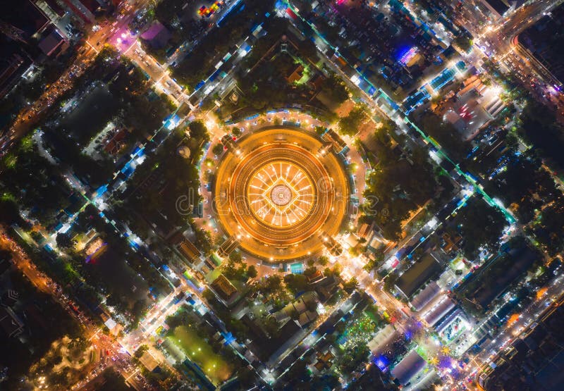 Aerial top view of Phra Pathommachedi temple at night. The golden buddhist pagoda with residential houses, urban city of Nakorn