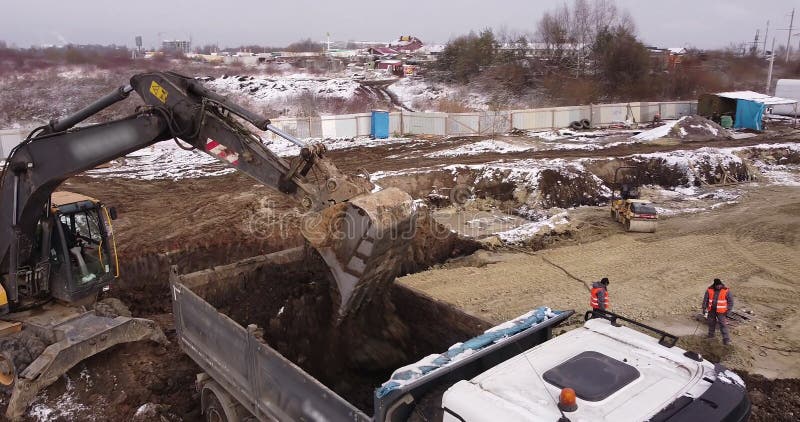 Aerial top view: yellow excavator pouring soil into tipper. Preparing place to construction residential house. top down royalty free stock image