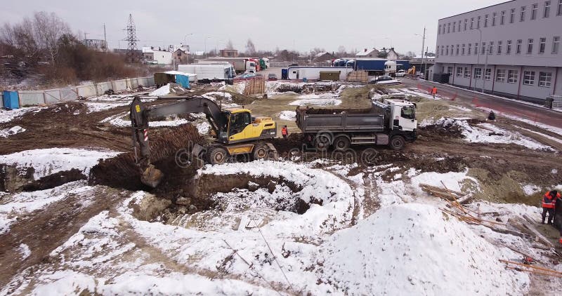 Aerial top view: yellow excavator pouring soil into tipper. Preparing place to construction residential house. top down royalty free stock photography
