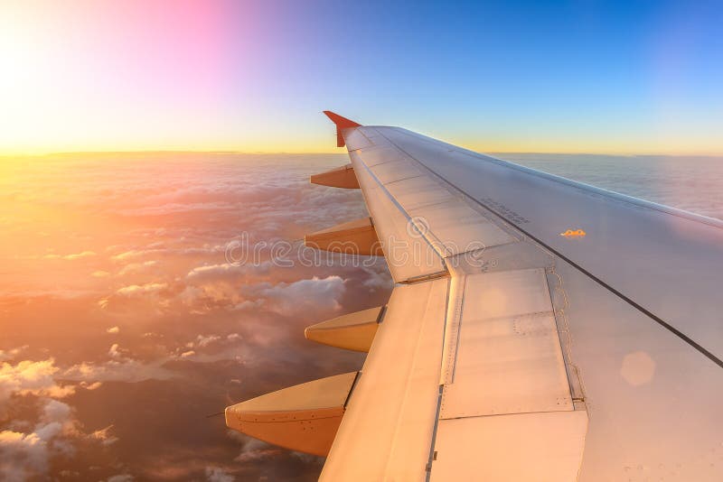 Aerial view of airplane flying above shade clouds and sky from an airplane fly during the sunset. View from the plane window.