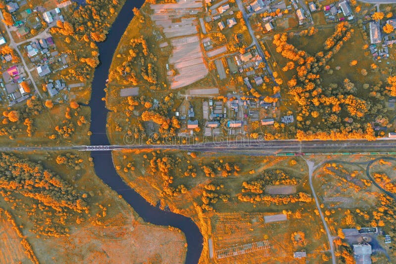 Aerial view autumn landscape of winding small river among the town, stream in orange colors nature field, top view